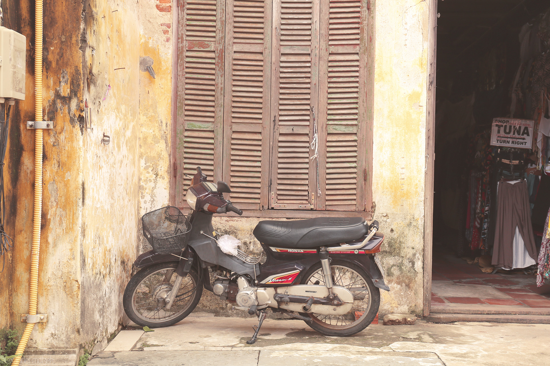 Foto von A classic Honda Dream leans against sun-kissed yellow walls of old Hoi An, Vietnam, echoing stories of quiet streets and timeless charm.