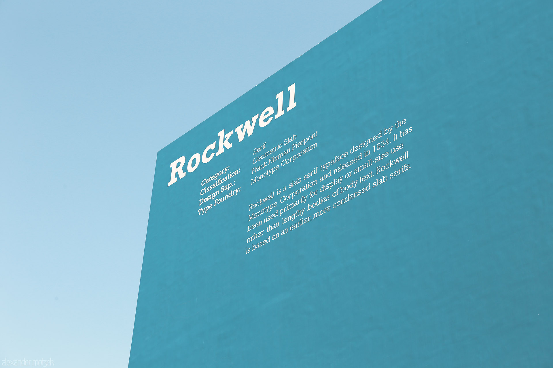 Foto von A minimalist blue wall in Dubai, adorned with 'Rockwell' typography, rises sharply under the clear Emirati sky.
