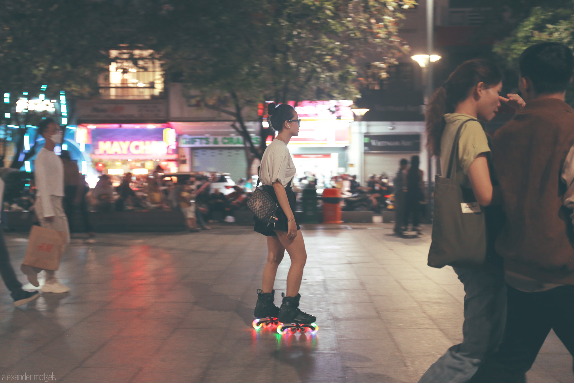 Foto von A skater glides on neon-lit wheels through Saigon’s buzzing Nguyen Hue  street, lights blurring into the electric night.