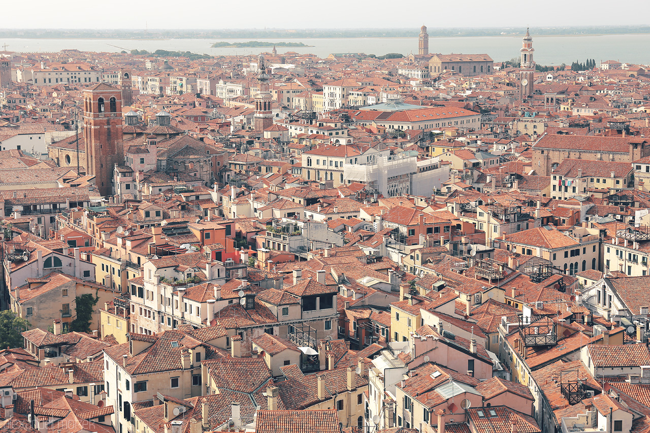 Foto von A sun-kissed expanse of Venetian rooftops, bell towers piercing the skyline, and the lagoon's shimmer in the distance.