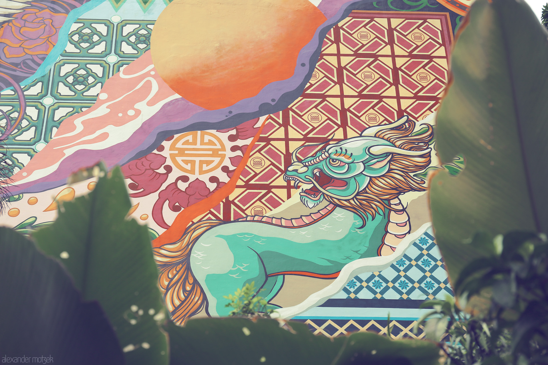 Foto von A vibrant dragon mural peeks through tropical leaves, capturing Singapore's cultural fusion and street art energy.