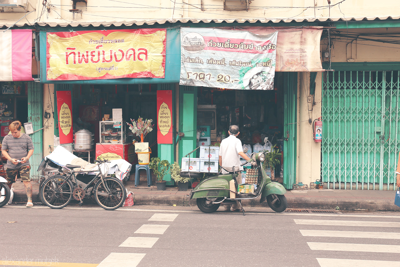 Foto von A lively scene in San Chao Pho Suea, Bangkok, showcasing vibrant street life, vintage scooters, and local shops full of character.