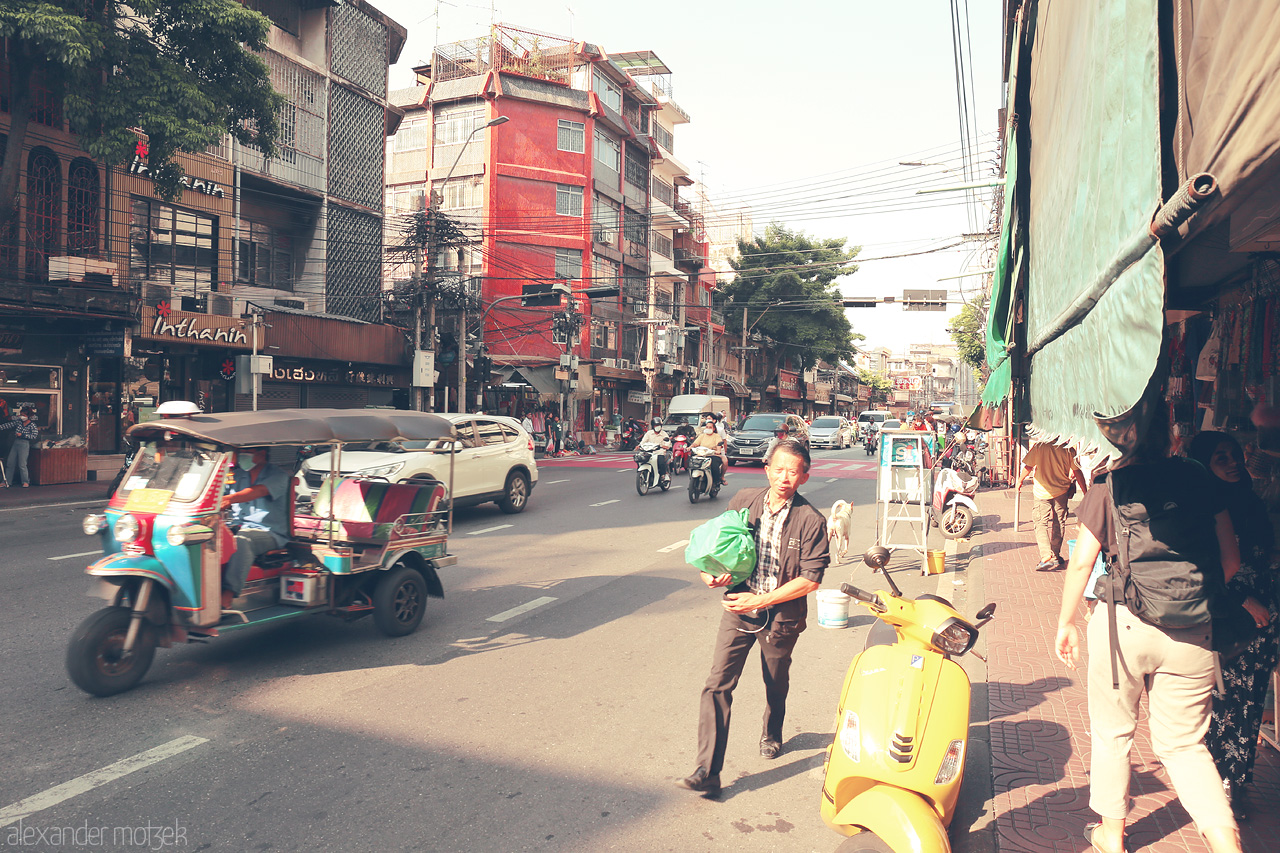 Foto von A vibrant scene in Chakkrawat, Bangkok, bustling with tuk-tuks, pedestrians, and street vendors under the afternoon sun.