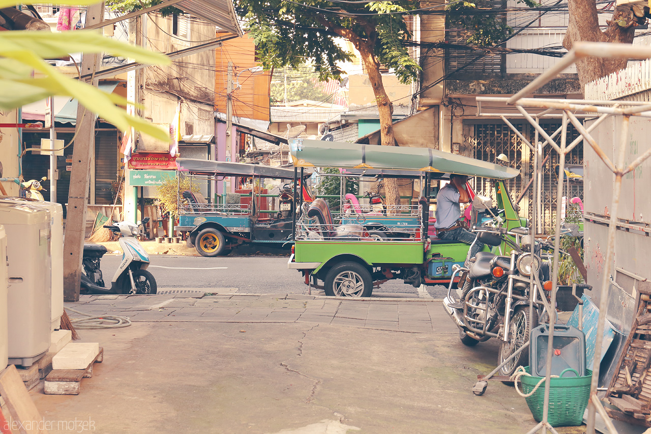 Foto von A vivid street scene in Khlong Maha Nak, Bangkok, capturing tuk-tuks and local life under dappled sunlight.