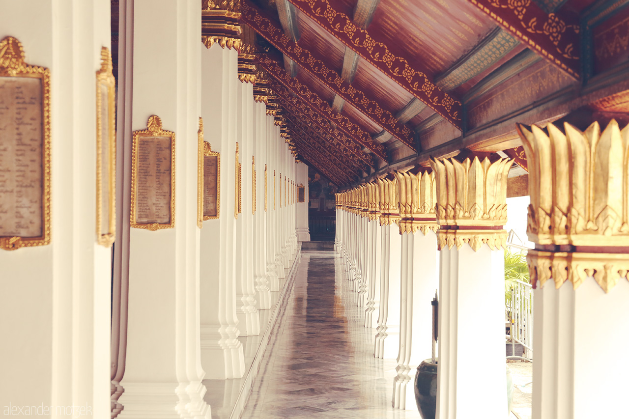 Foto von Golden-capped columns line a serene corridor at Phra Borom Maha Ratchawang, capturing Bangkok's architectural elegance.