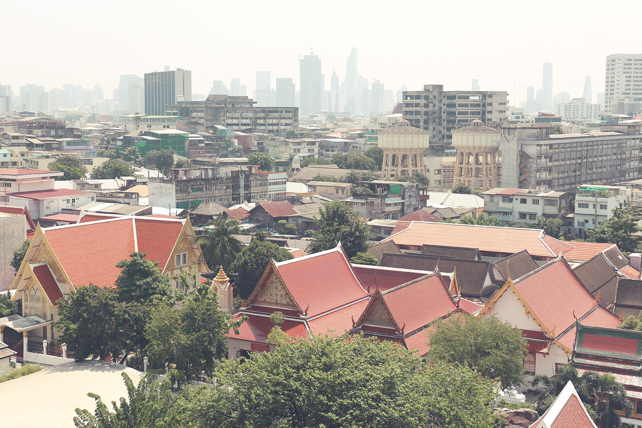 Foto von Historic rooftops of Ban Bat, Bangkok, with vibrant temples against a backdrop of modern skyscrapers, blending tradition with urban life.