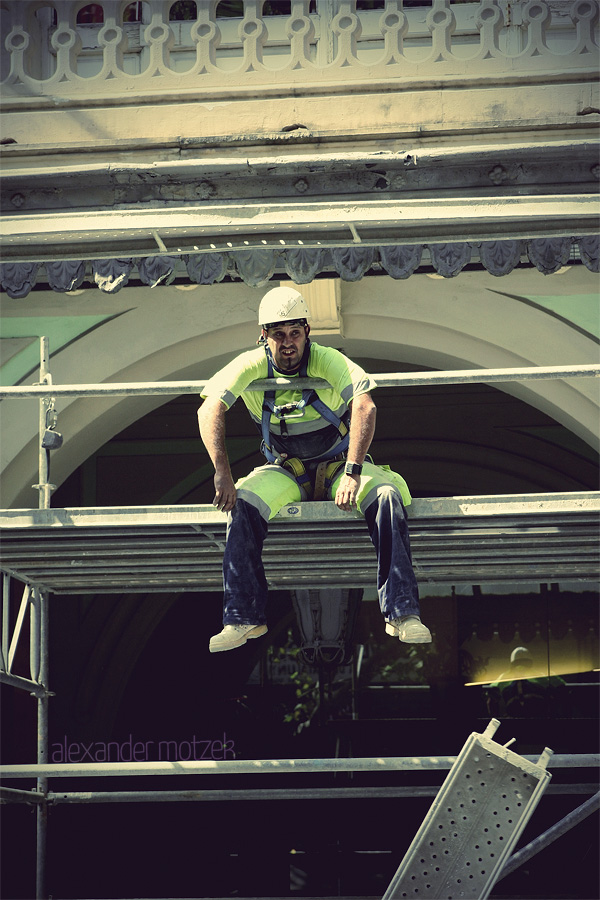 Foto von A construction worker rests on scaffolding with Barcelona's vibrant architecture in the backdrop, embodying the city's blend of old and new.