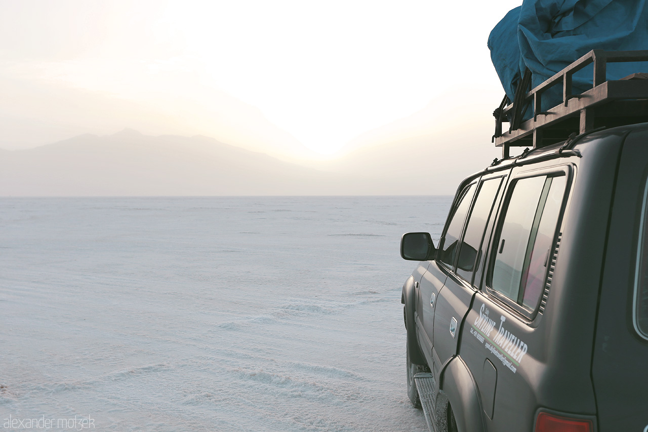 Foto von A 4x4 Toyota Land Cruiser silhouetted against the ethereal expanse of Salar de Uyuni in Municipio Colcha K, Bolivia, at dusk.