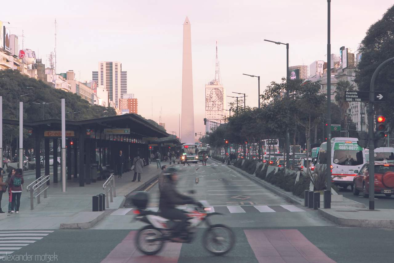 Foto von Bustling Avenida 9 de Julio in Buenos Aires, with the iconic Obelisco at sunset and lively traffic symbolizing the city's heartbeat.