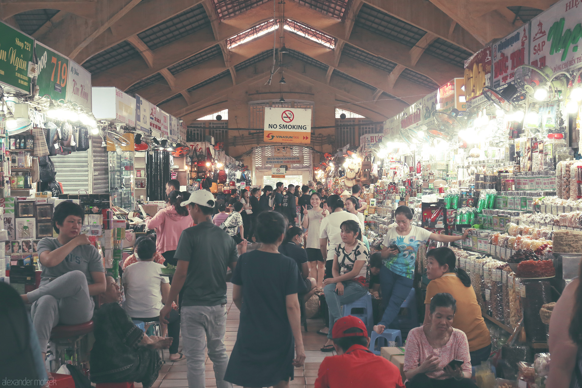 Foto von Bustling life in Ben Thành Market, Ho Chi Minh City — locals and traders merge in vibrant chaos, under warm lights and soaring arches.