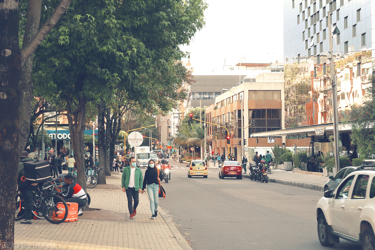 Foto von A bustling street in Chapinero, Bogotá, Colombia, showcasing daily city life with people walking, cars driving, and a mix of modern and traditional architecture.