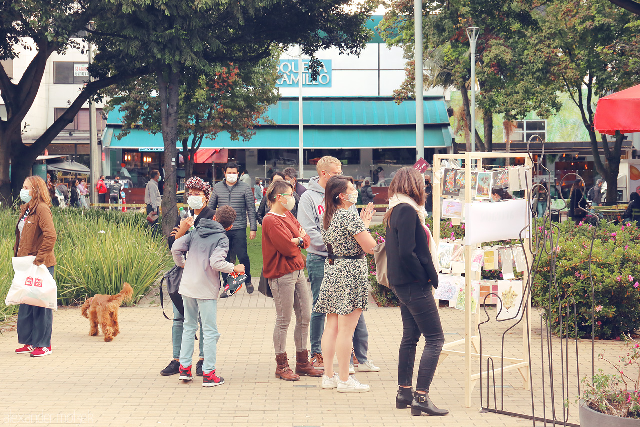 Foto von A lively scene in Parque 93, Chapinero, Bogotá, Colombia, where people are exploring local art in a bustling square filled with greenery and urban charm.