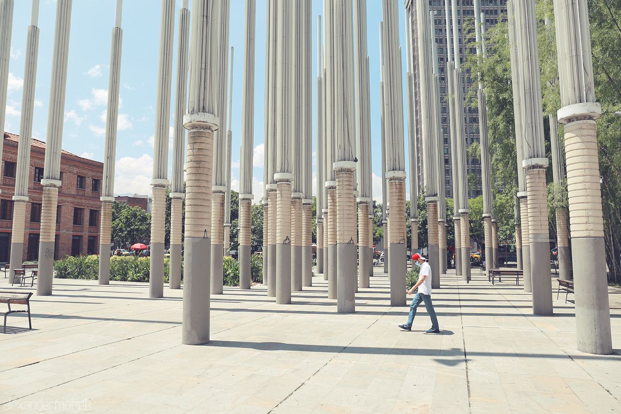 Foto von A man walks through tall columns in Comuna 10 - La Candelaria, Medellín, Colombia, offering a glimpse of the vibrant urban life.