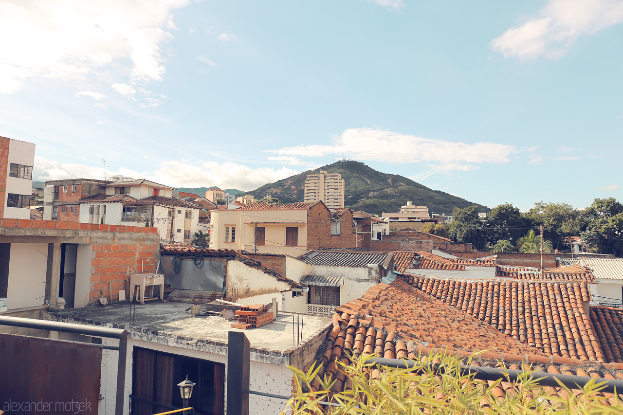 Foto von A picturesque view of the rooftops in Comuna 3, Cali, Colombia, with the iconic Tres Cruces hill dominating the background.