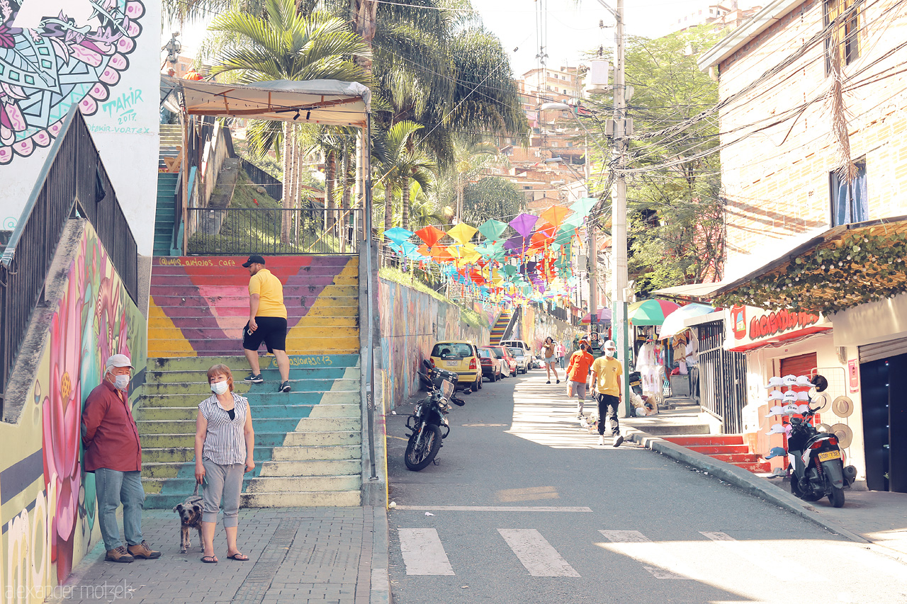 Foto von A snapshot of Comuna 13, Medellín showcasing vibrant street art, colorful flags, and local life amidst bustling streets.