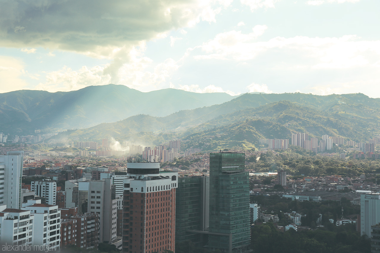 Foto von A stunning view of Comuna 14 - El Poblado in Medellín, Colombia, with cityscape merging into the verdant Andean mountains under a dramatic sky.