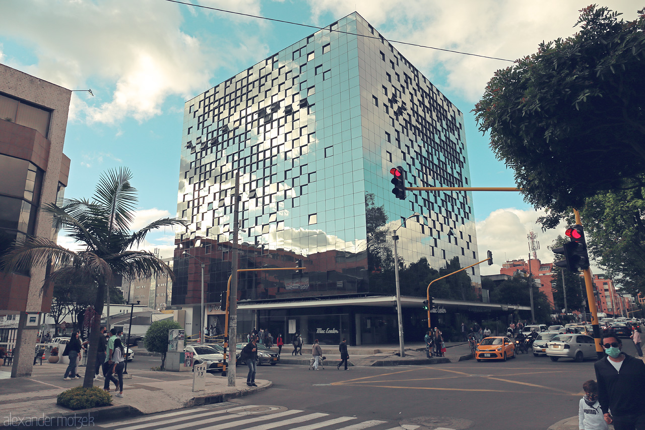 Foto von A vibrant corner of Chapinero, Bogotá, capturing the essence of urban life with a stunning reflective glass building under a vibrant sky.