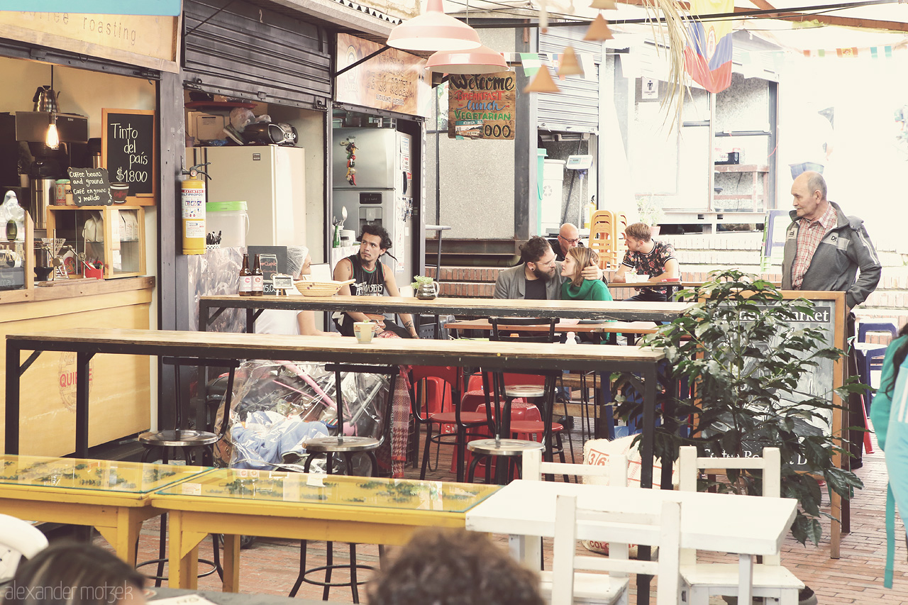 Foto von A vibrant moment at a cozy café in La Candelaria, Bogota, capturing everyday life and local charm. Amor en el andén y sabor colombiano.