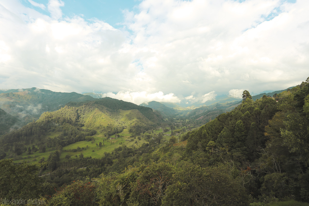 Foto von An expansive view of Salento's lush green valley. Quindío's rolling hills and dramatic skies captured in a serene moment.