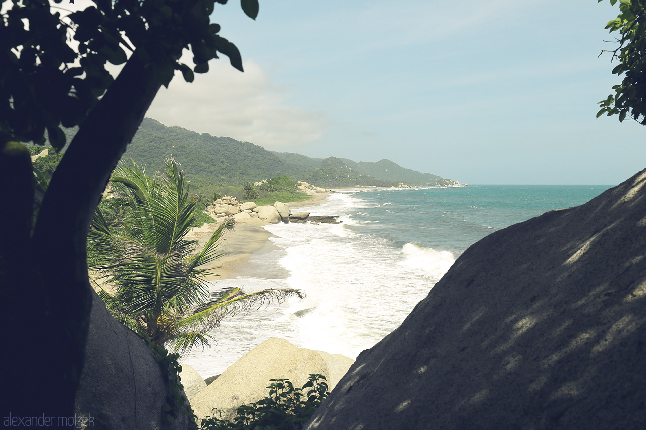 Foto von Breathtaking coastal view of Tayrona, Santa Marta, Colombia, where lush mountains meet the turquoise ocean through a frame of tropical foliage.