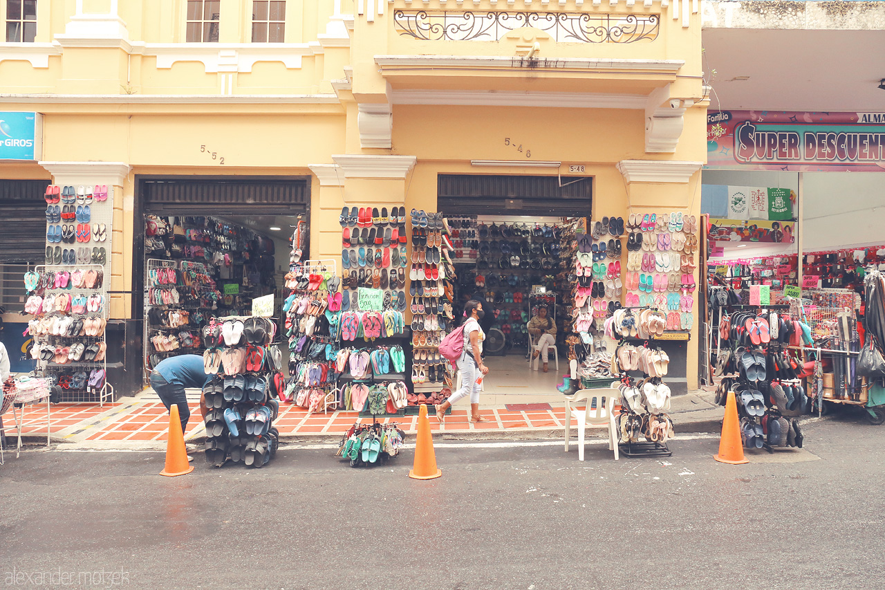 Foto von Bustling market scene in Comuna 3, Cali, Colombia, showcasing vibrant storefronts with endless rows of colorful sandals and shoes.