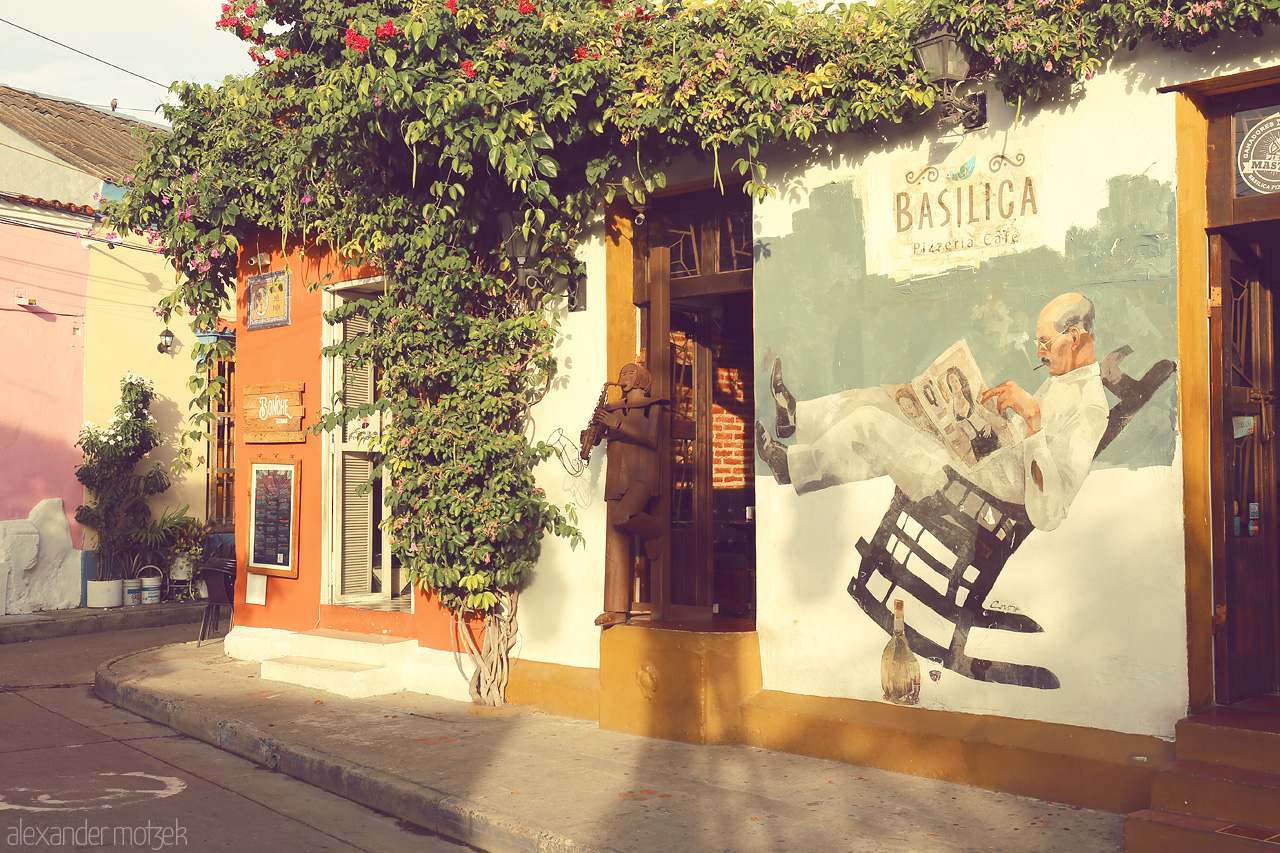 Foto von Vibrant Cartagena street scene with colorful walls and a mural of a man lounging, encapsulating the city's charm.