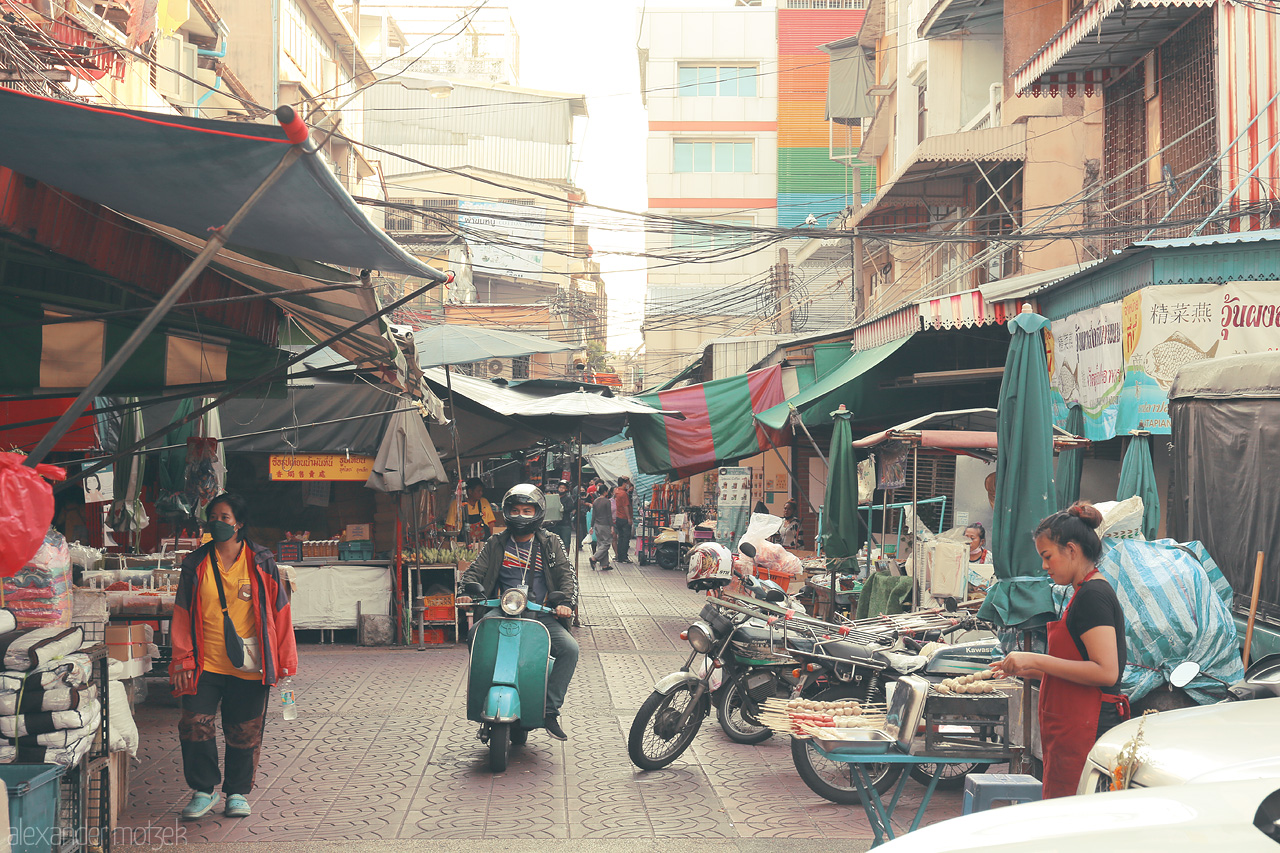 Vibrant Vibes of Chakkrawat Foto von Dive into the bustling energy of Chakkrawat, Bangkok. Scooters weave through vibrant market stalls, capturing the relentless pulse of local life.