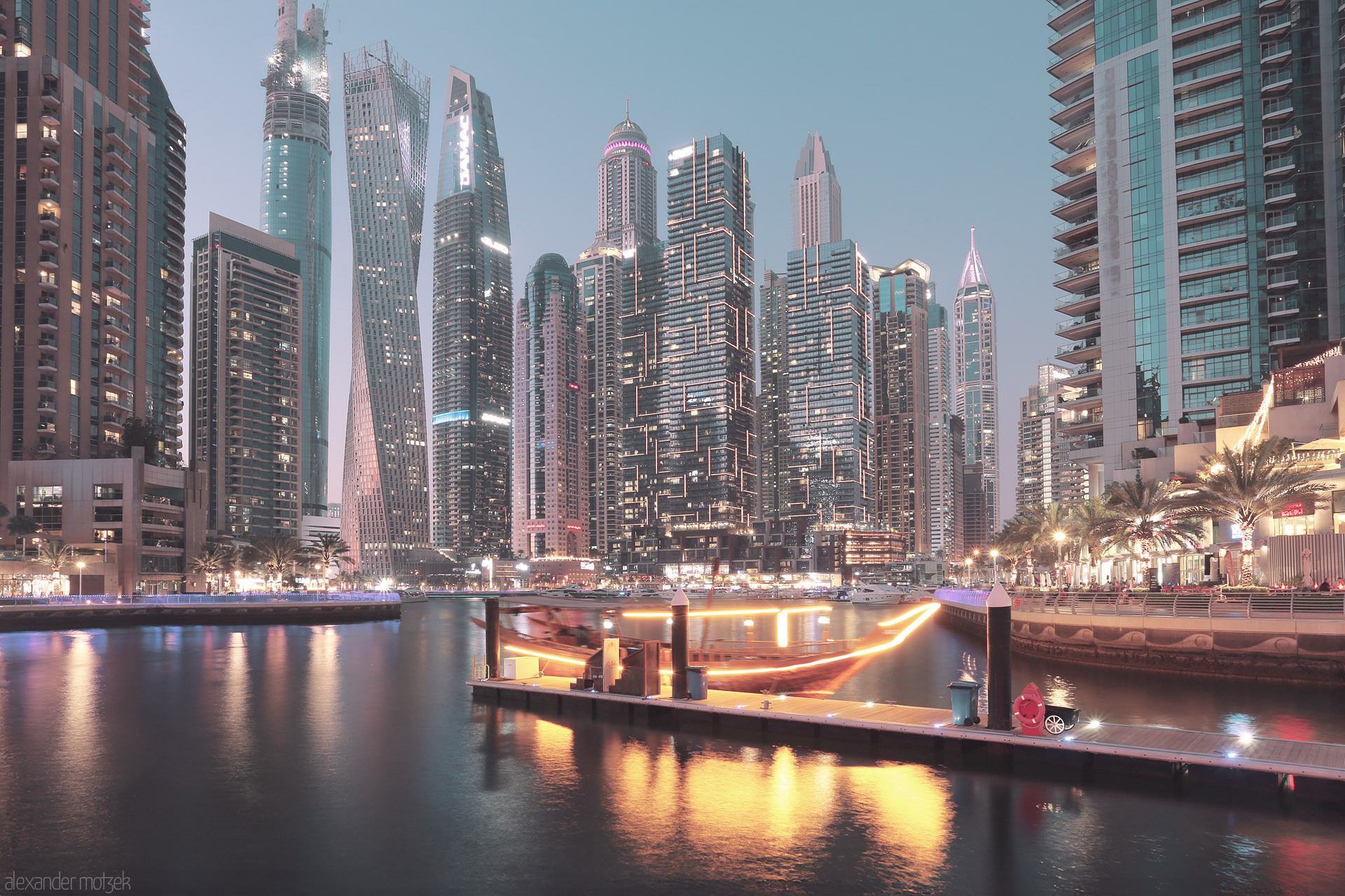 Marina Mashreq Foto von Dubai Marina aglow at dusk, where futuristic towers and a glowing dhow create a shimmering, modern oasis on tranquil waters.