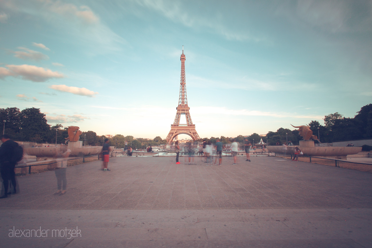 Foto von Dusk at the Eiffel Tower in Paris; blurred figures stroll under pastel skies, capturing an ethereal moment in the City of Light.