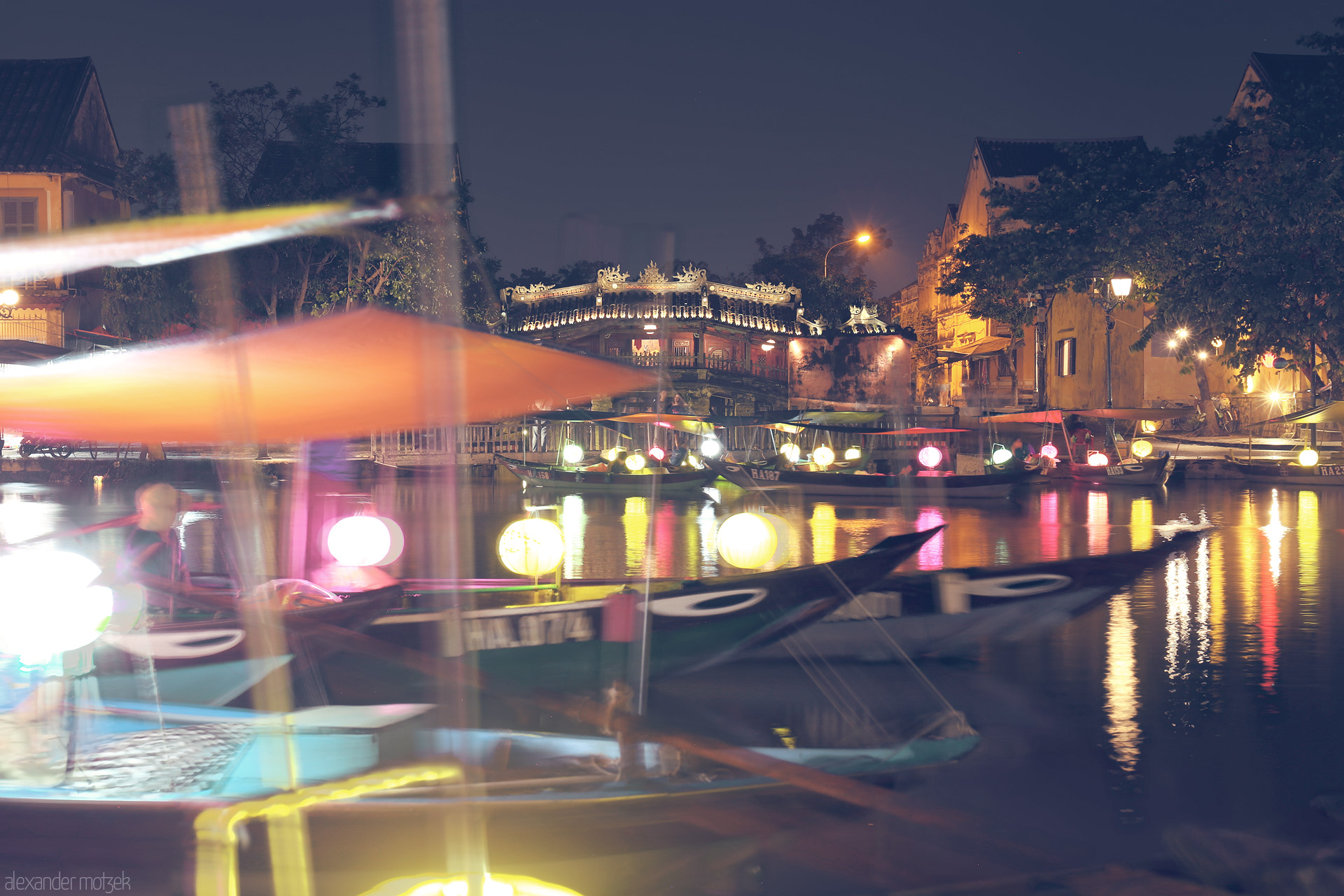 Foto von Glowing lanterns drift on Hoi An’s Thu Bon River, reflecting centuries-old charm under the ancient Chùa Cau bridge at night.