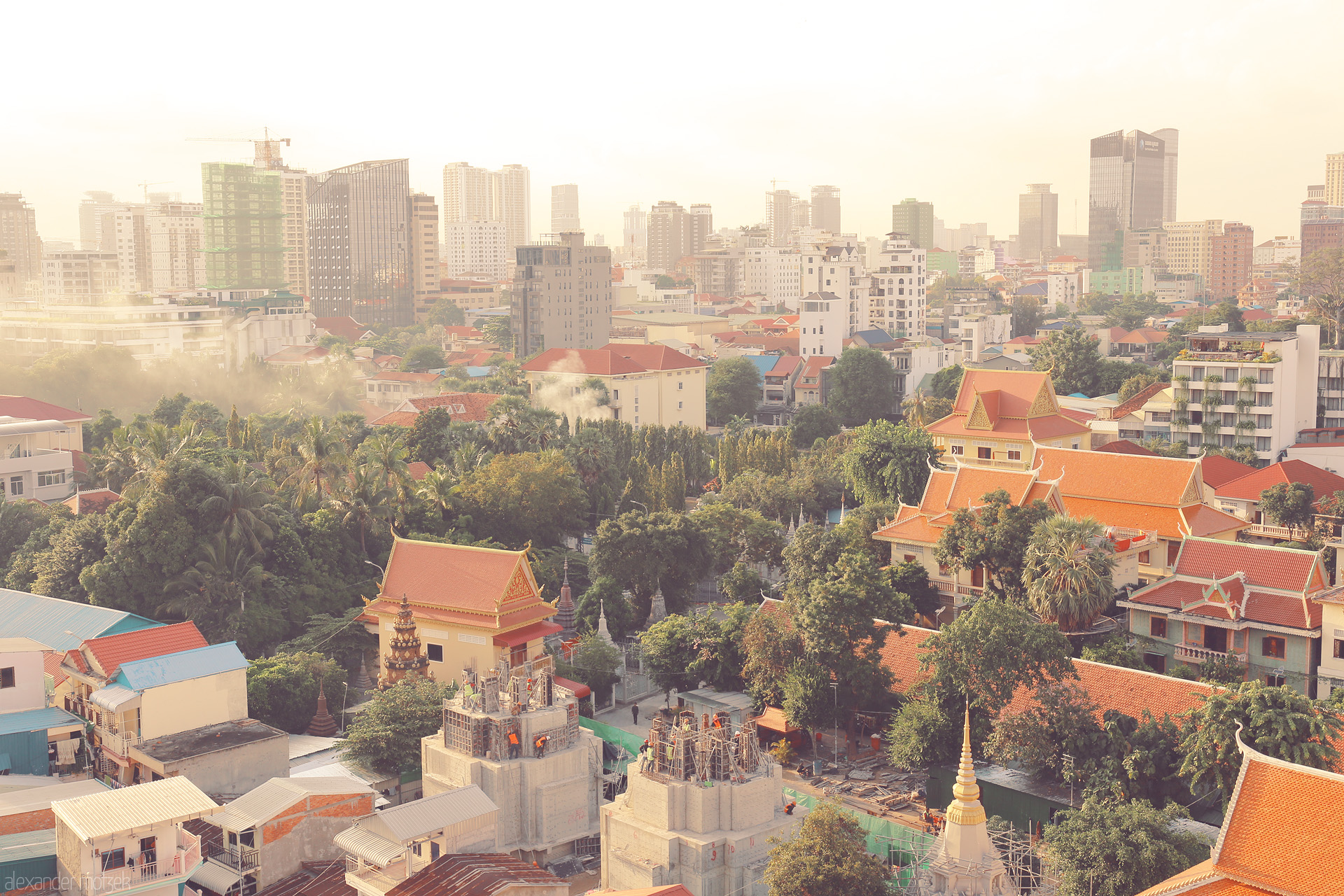 Foto von Golden dawn bathes Phnom Penh's red-roofed pagodas and rising skyline in a tranquil blend of tradition and modernity.