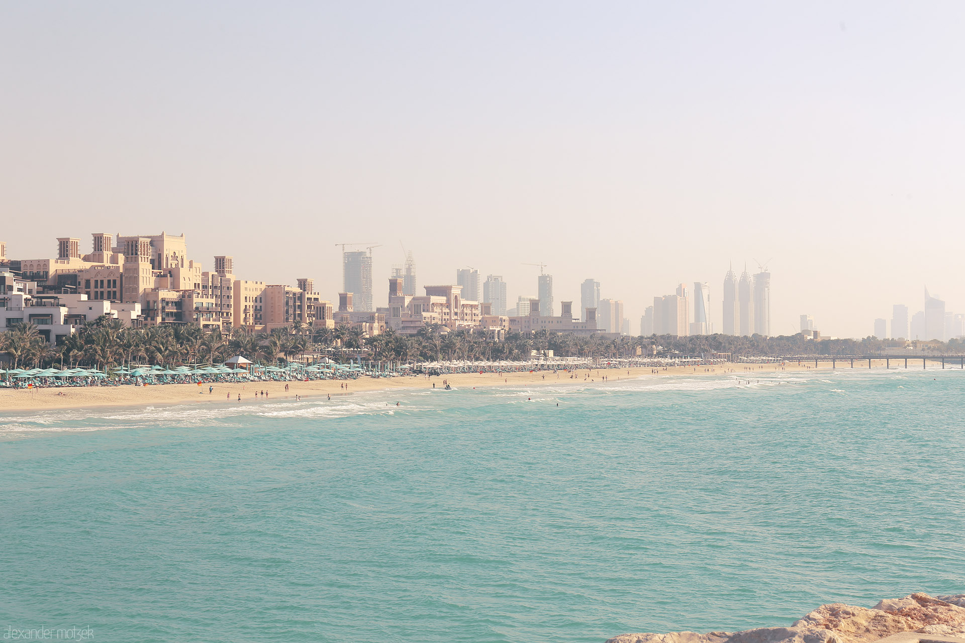 Foto von Golden sands meet Arabian architecture, as Dubai’s skyline rises through the morning haze at Jumeirah Beach.