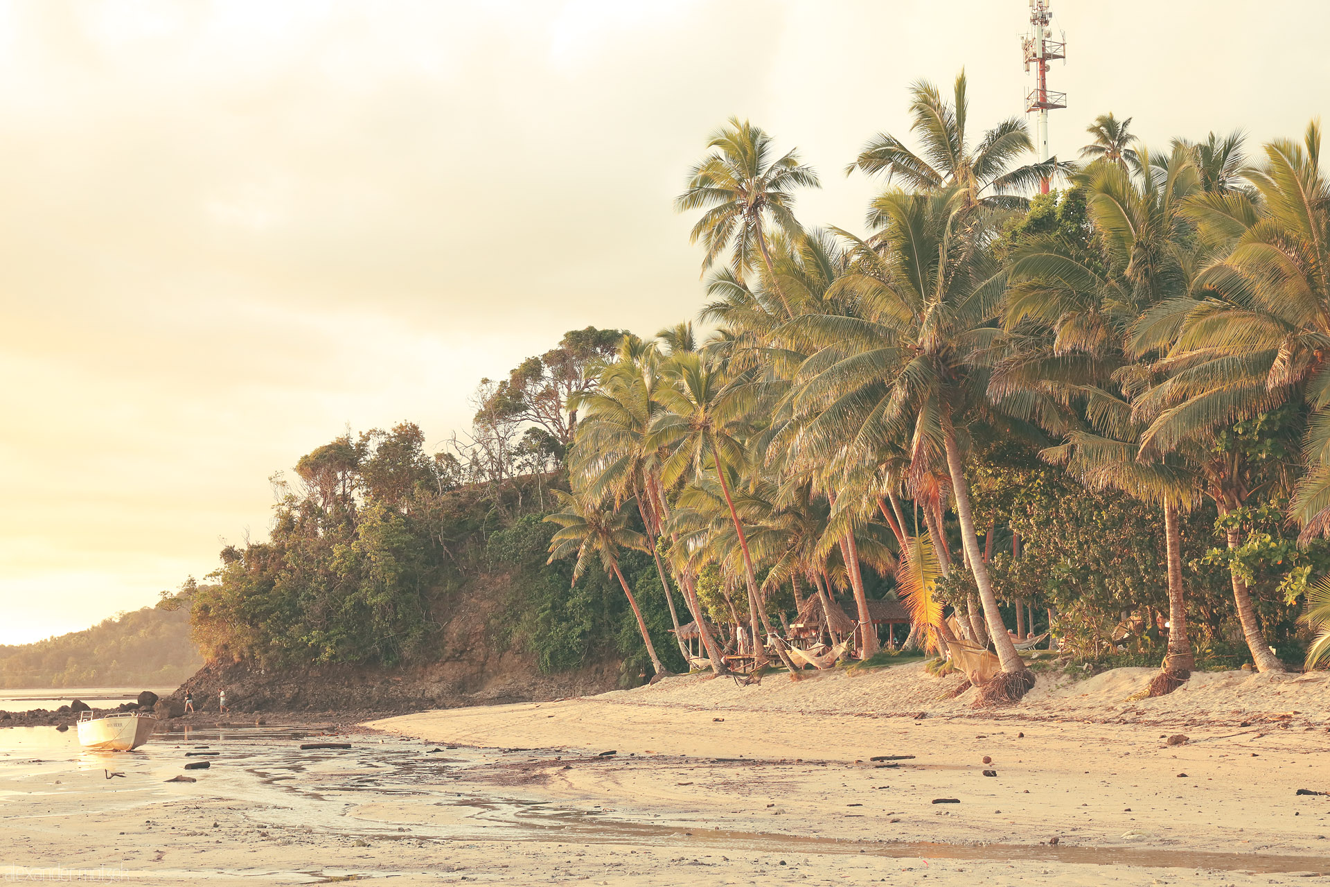 Foto von Golden-hour low tide on Komave Beach, Fiji—leaning palms, hammocks in shade, and a skiff waiting in the shallows.