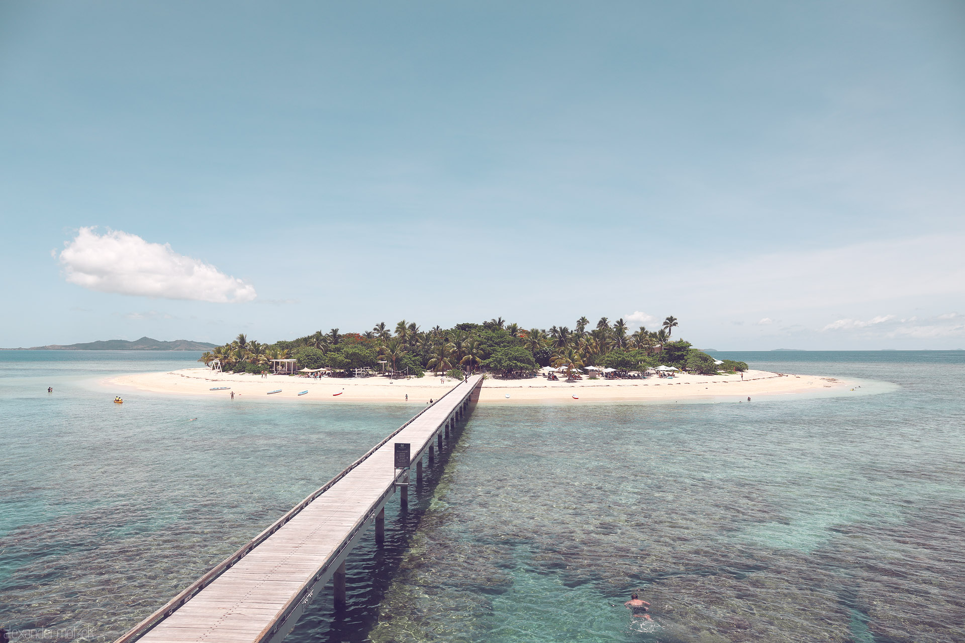 Foto von Long wooden pier reaches a palm-fringed sandbar over clear turquoise lagoon, Mamanuca Islands, Fiji.