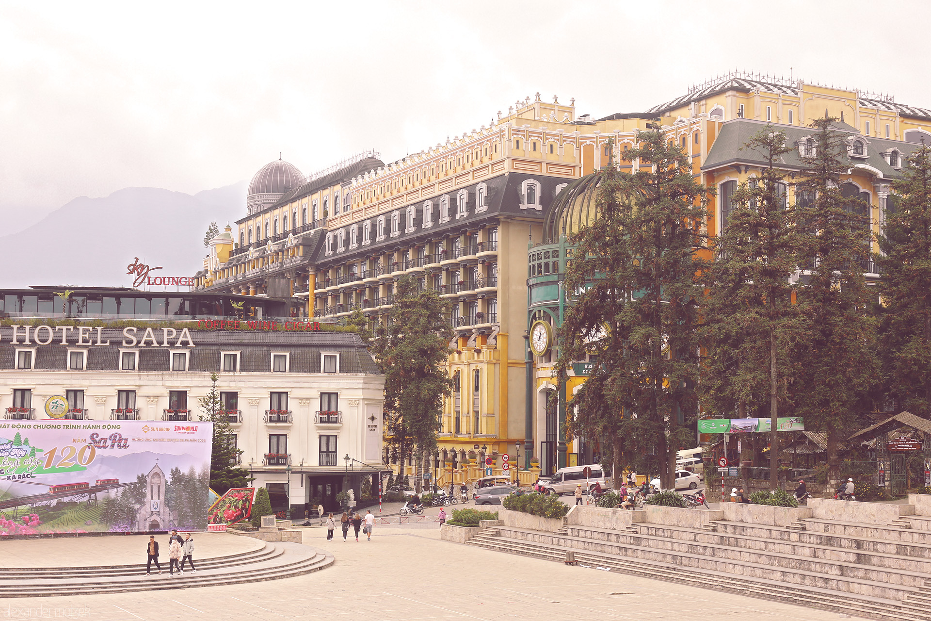 Foto von Majestic hotels rise through misty Sapa, Vietnam—French Indochine meets mountain serenity in a lively plaza framed by pines.