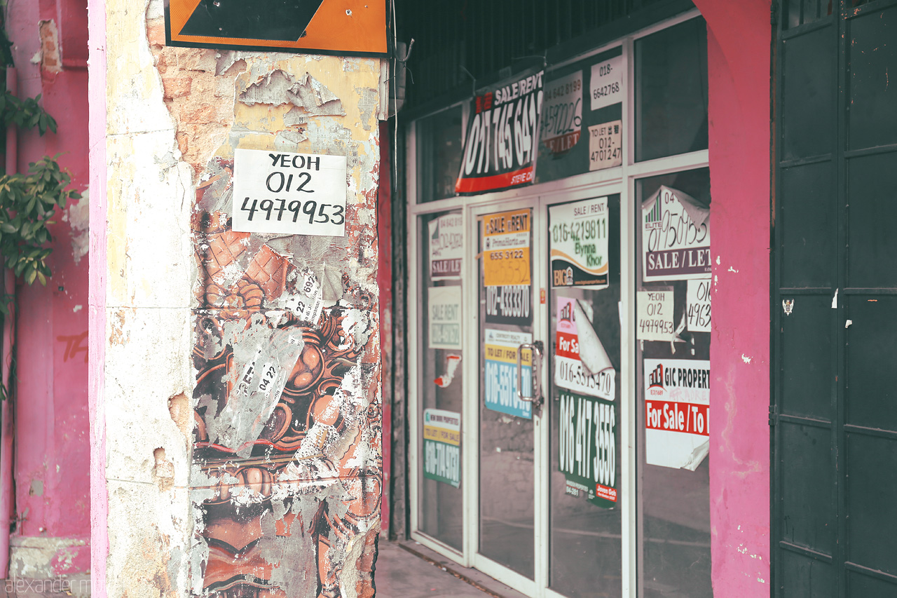 Foto von A collage of vibrant sale signs and weathered walls in Penang captures the city's colorful blend of history and modern life.