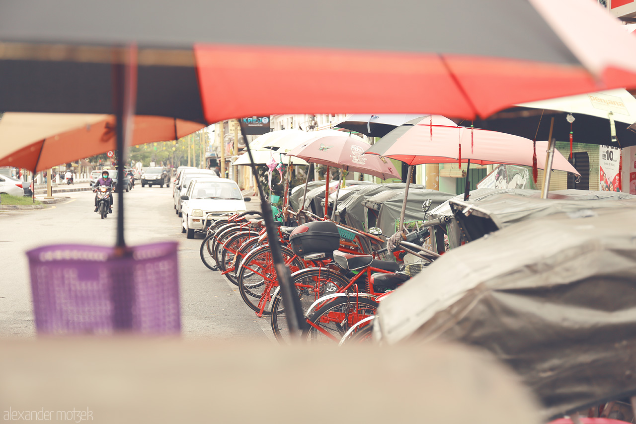 Foto von A vibrant assembly of trishaws under colorful umbrellas in bustling Penang, Malaysia.