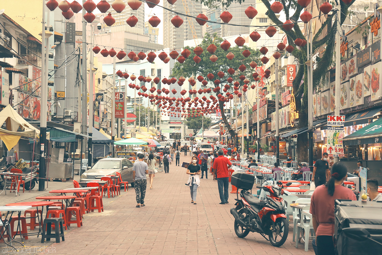 Foto von Bustling street in Kuala Lumpur adorned with red lanterns and vibrant stalls. Experience the lively heart of Malaysia's culture and cuisine.