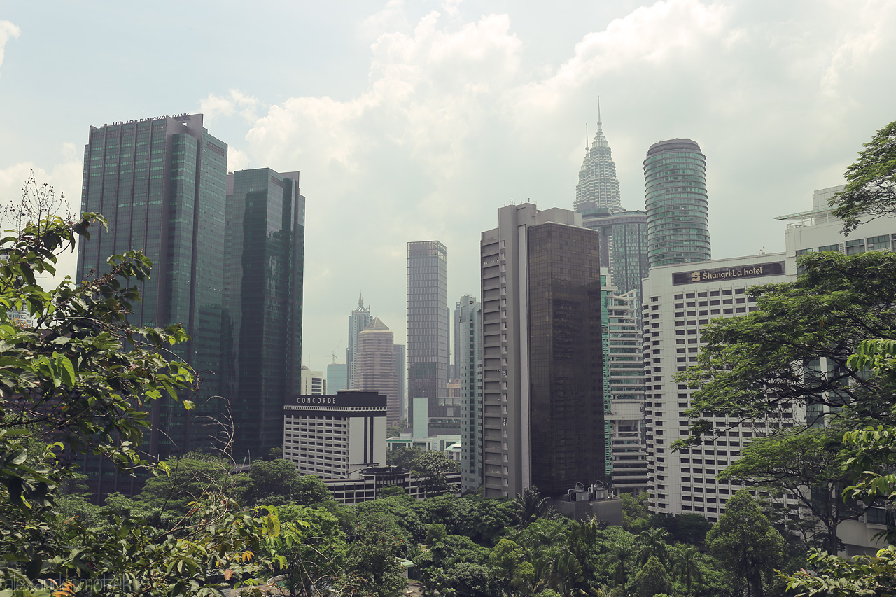 Foto von Explore the lush green meeting the soaring skyscrapers of Kuala Lumpur, crowned by the iconic Petronas Towers under a soft, cloudy sky.