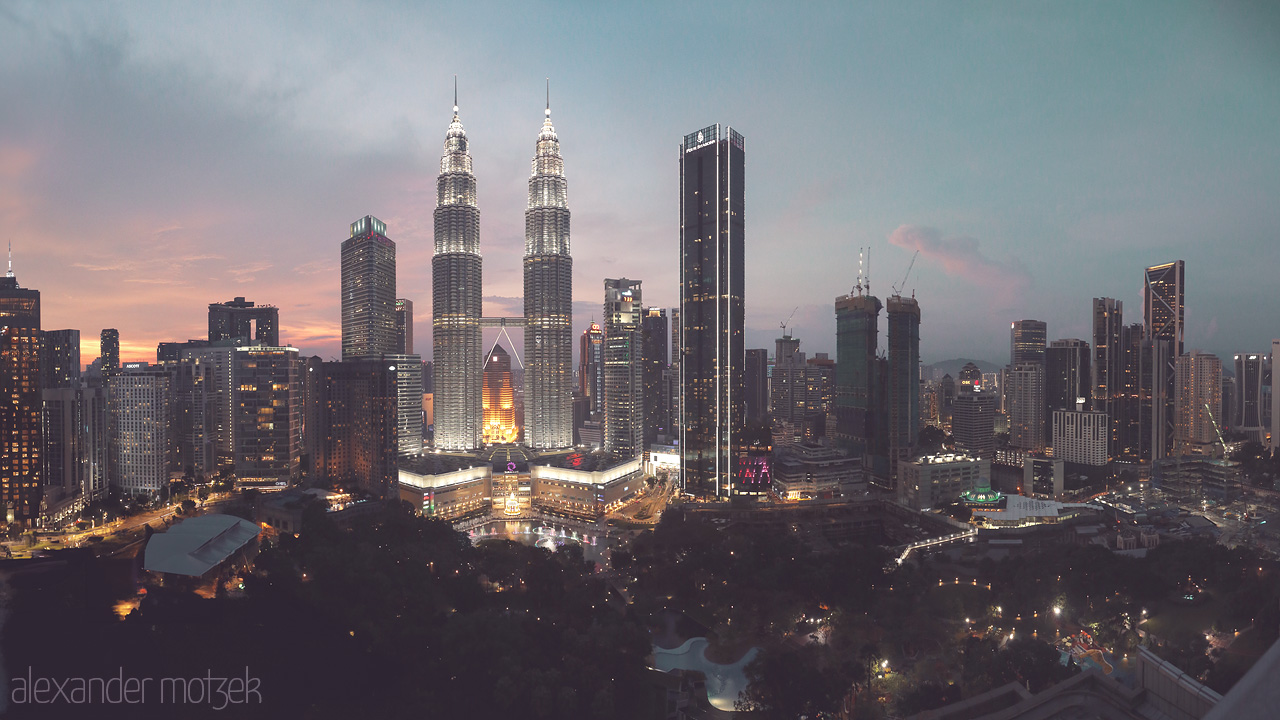 Foto von The dazzling Petronas Towers illuminate Kuala Lumpur's skyline at dusk, blending urban artistry with the serene evening sky.