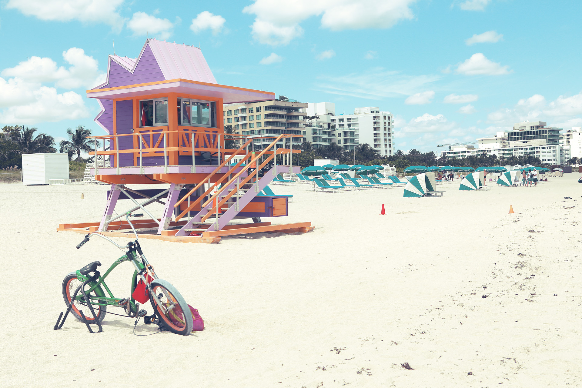 Foto von A vibrant lifeguard tower and cruiser bike on Miami's iconic South Beach under a cloud-swept sky.