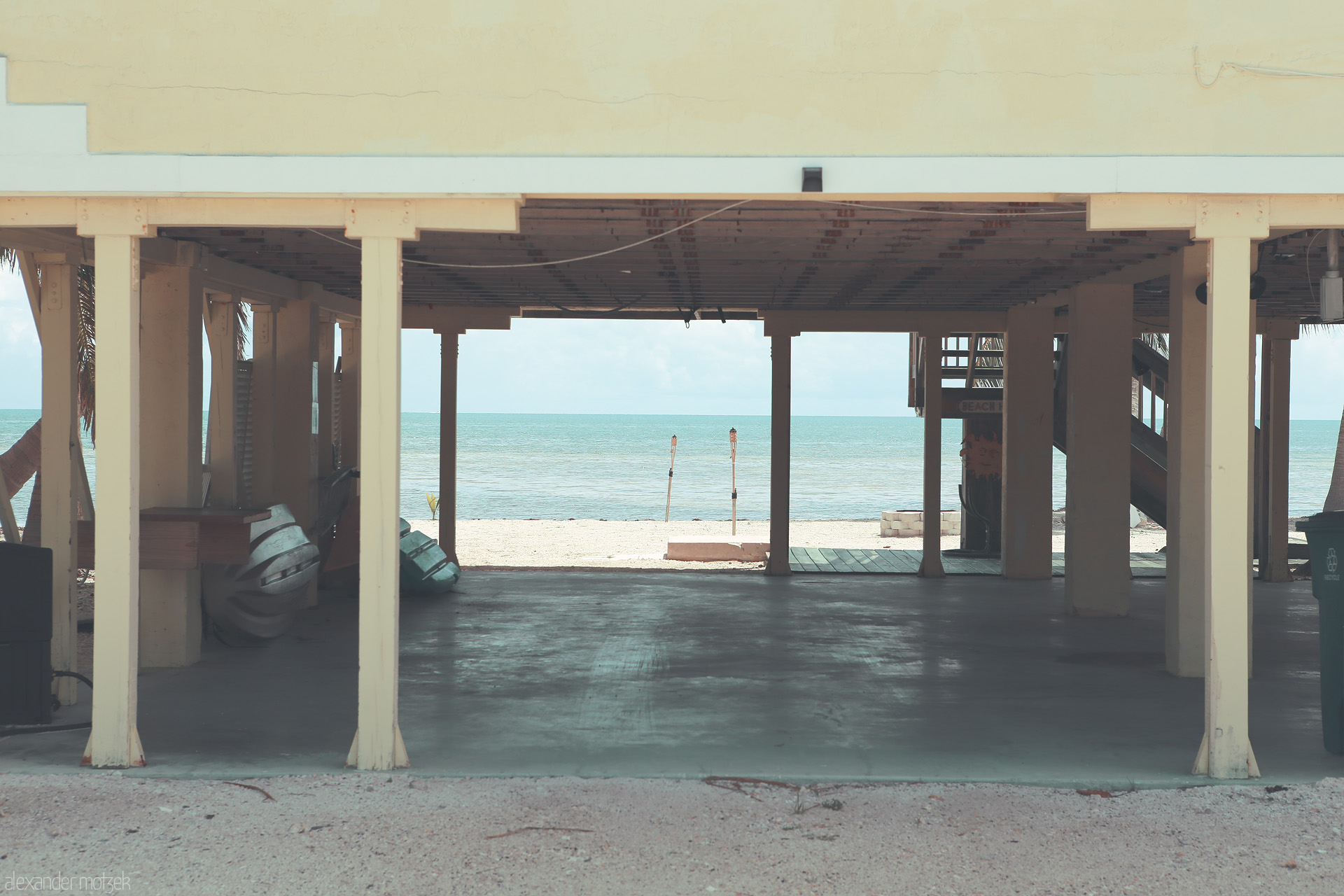 Foto von Sunlit beach shack in Monroe County with open view of the serene ocean through rustic pillars.