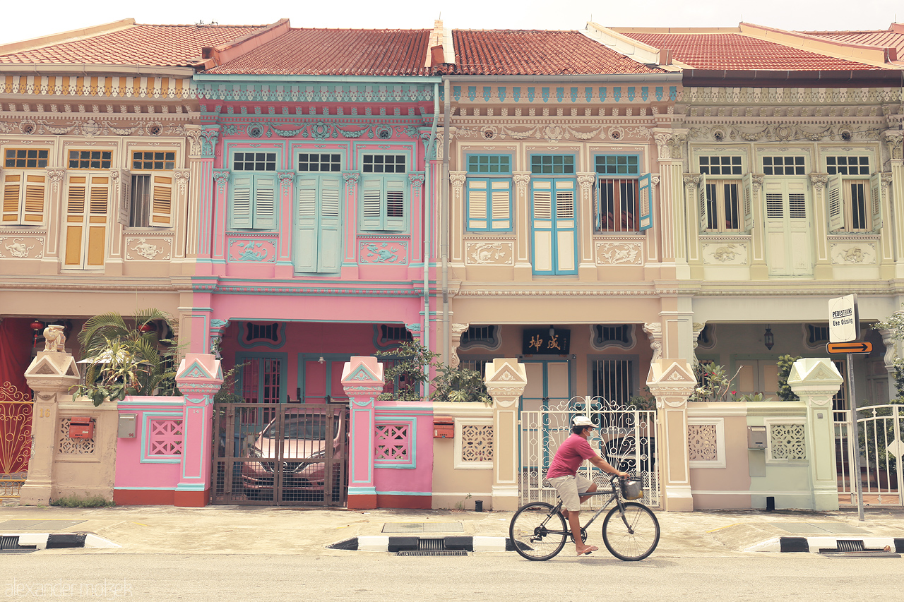 Foto von A cyclist passes iconic pastel-colored Peranakan houses in the vibrant Joo Chiat neighborhood, Singapore.