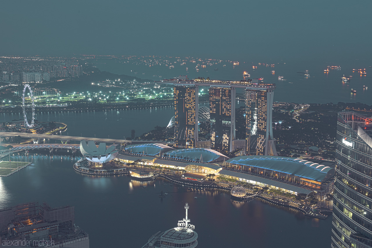 Foto von A panoramic view of Singapore's iconic Marina Bay Sands and Flyer, glowing against the twilight skyline and bustling bay.