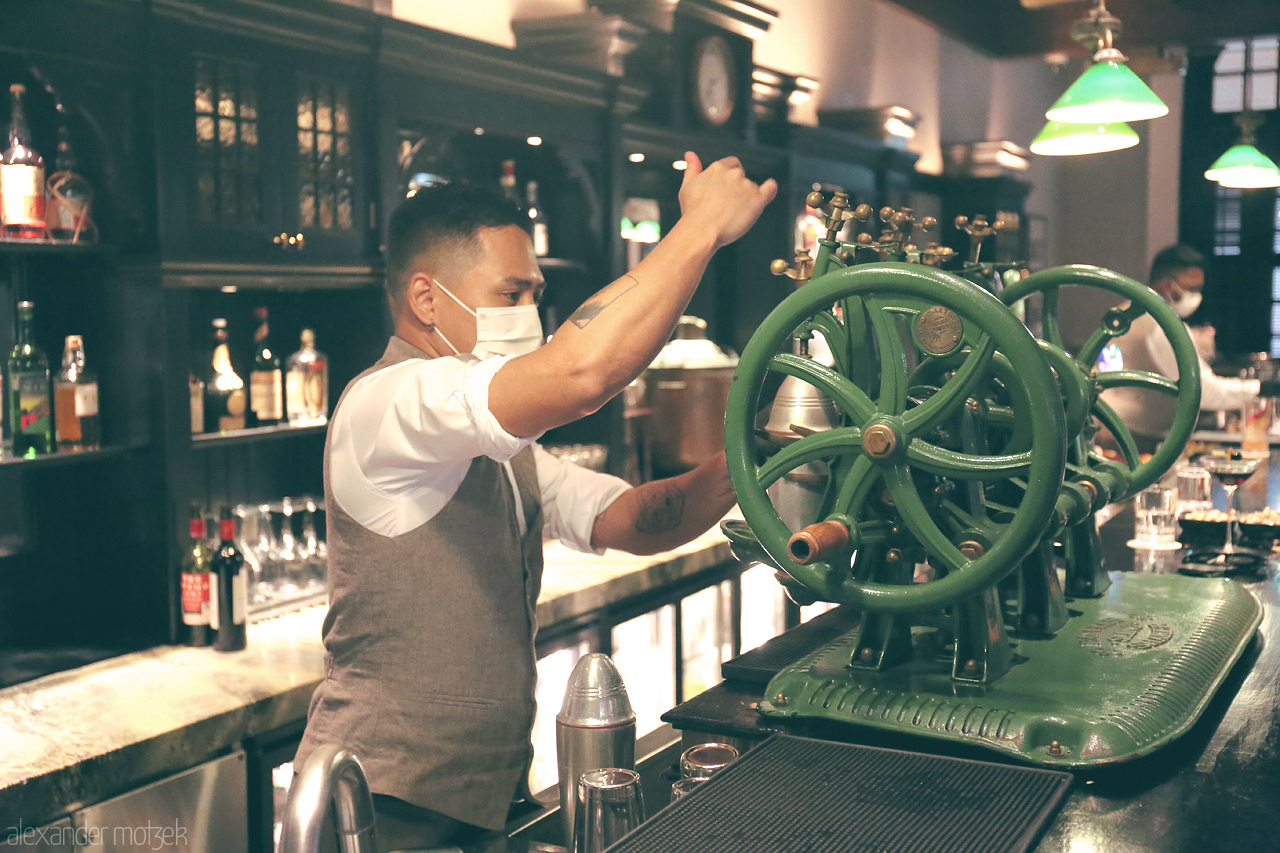 Foto von A skilled bartender crafts a drink using vintage equipment in an elegant, historic bar in Singapore, blending tradition with modern mixology.