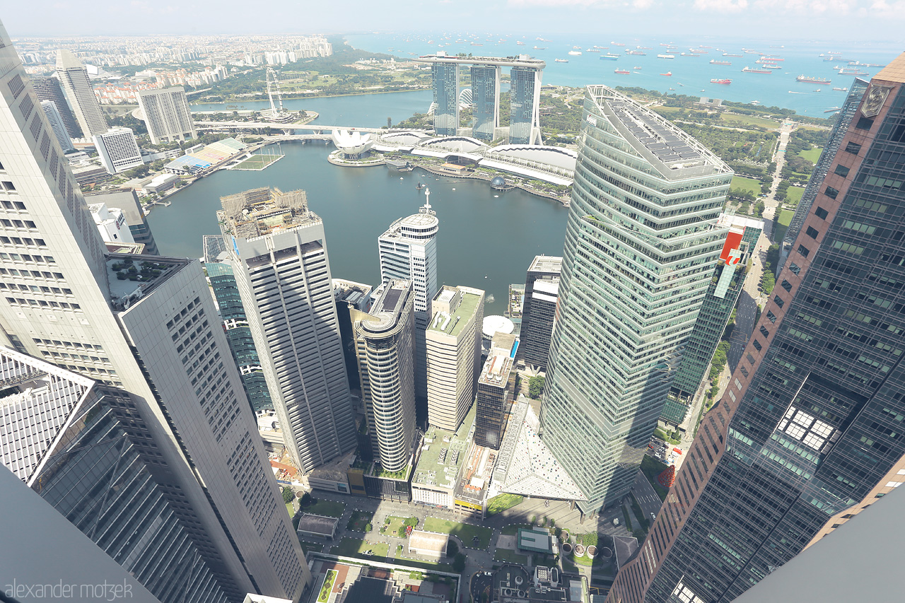 Foto von Explore Singapore from above, with Marina Bay Sands and the azure sea framing the skyline's architectural marvels.