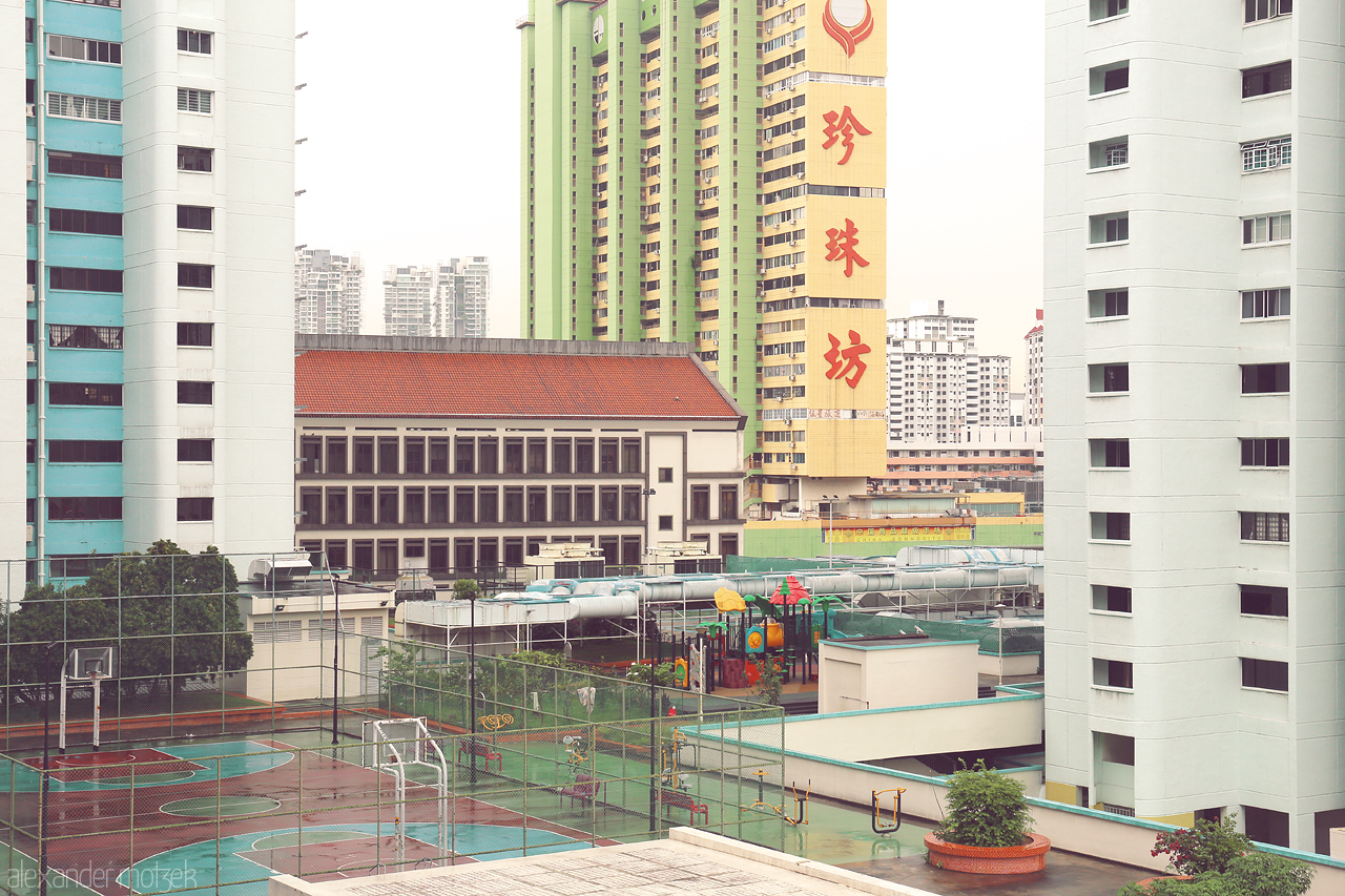 Foto von Singapore's cityscape blending high-rise buildings with a serene basketball court and playground within Chinatown district.