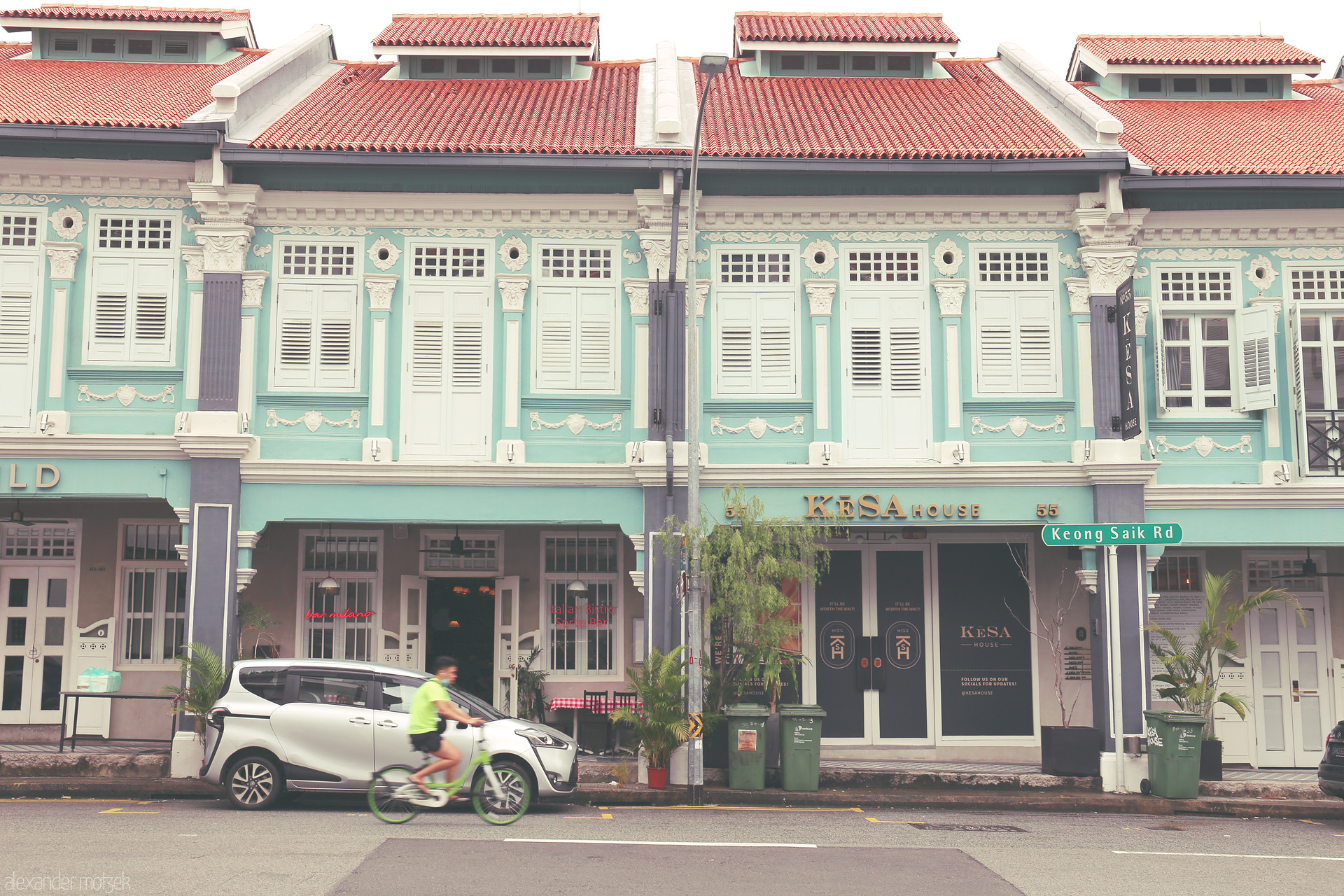 Foto von Turquoise Peranakan shophouses and a cyclist blend heritage and movement on historic Keong Saik Road, Singapore.