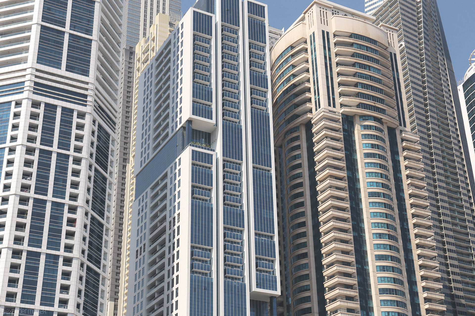 Foto von Soaring modern towers in Dubai's Marina, a geometric dance of sunlit glass and steel against the cloudless desert sky.