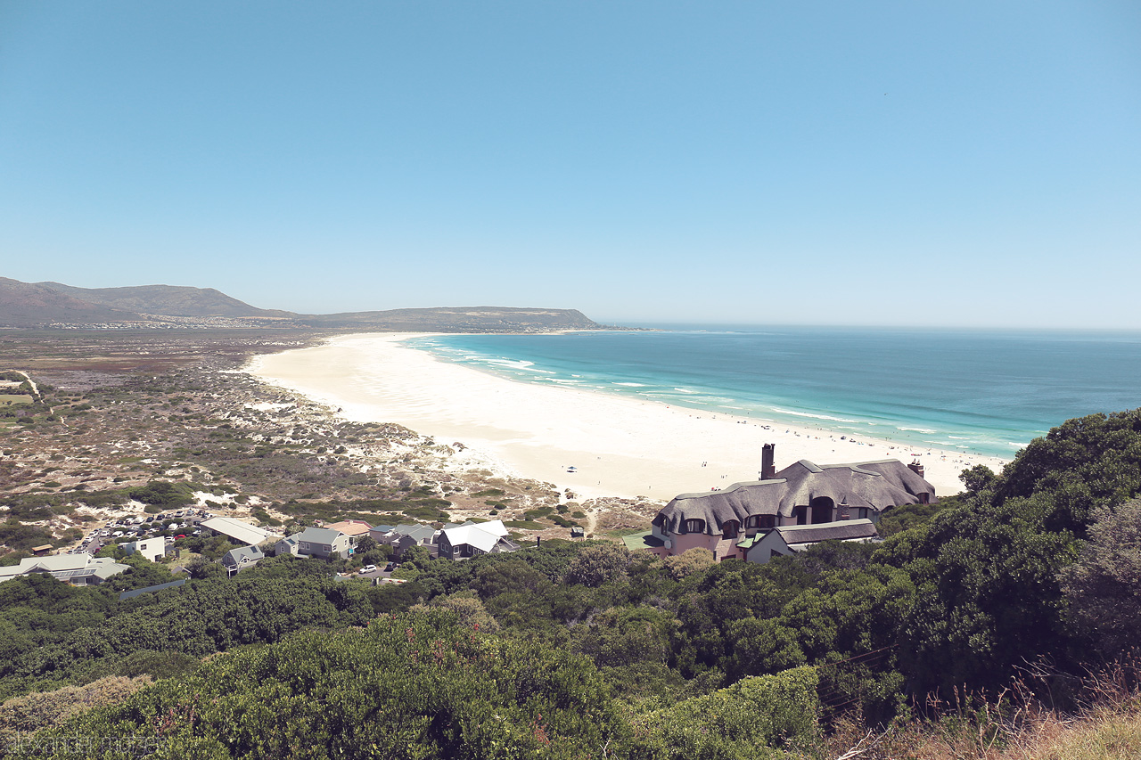 Foto von Gaze down on Cape Town’s stunning coastline, where the azure Atlantic meets sprawling sandy shores under a clear sky. A serene South African vista.